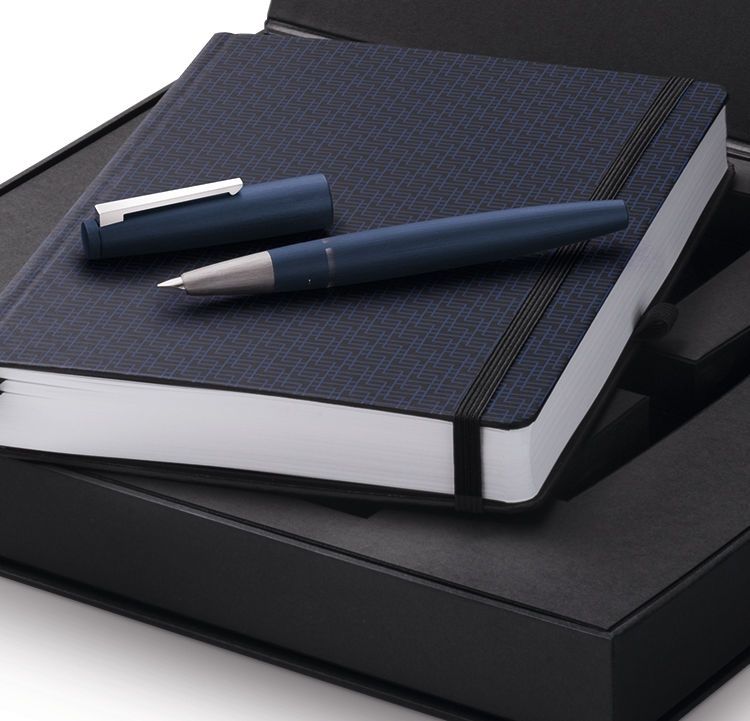 a streamlined blue fountain pen with a hooded nib, sitting on a book