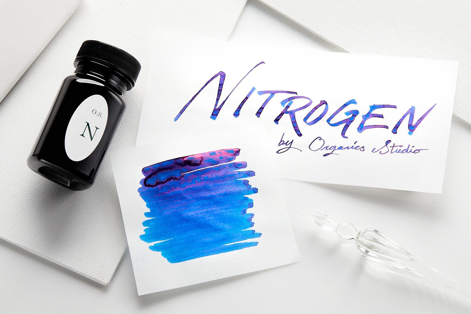 Bottle and swatch of a vivid blue ink with a glossy pink sheen