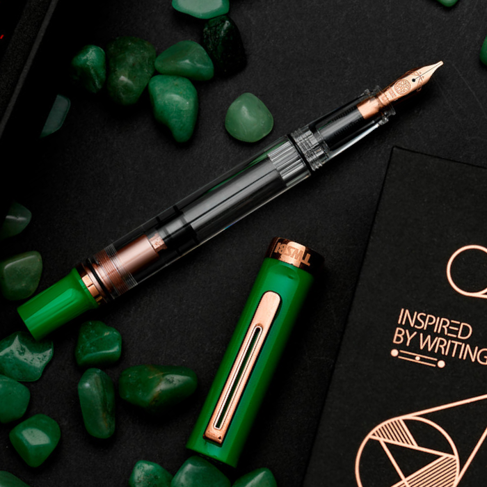 a chunky green pen with green ends and rose gold trim and internals, surrounded by green stones, nearby it says 'inspired by writing'