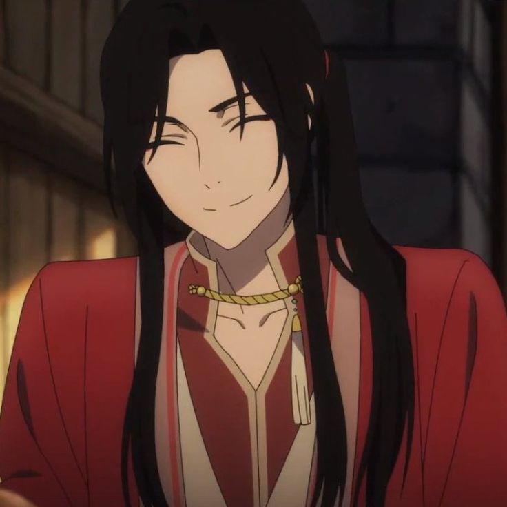 a smiling young man in red with wonky ponytail