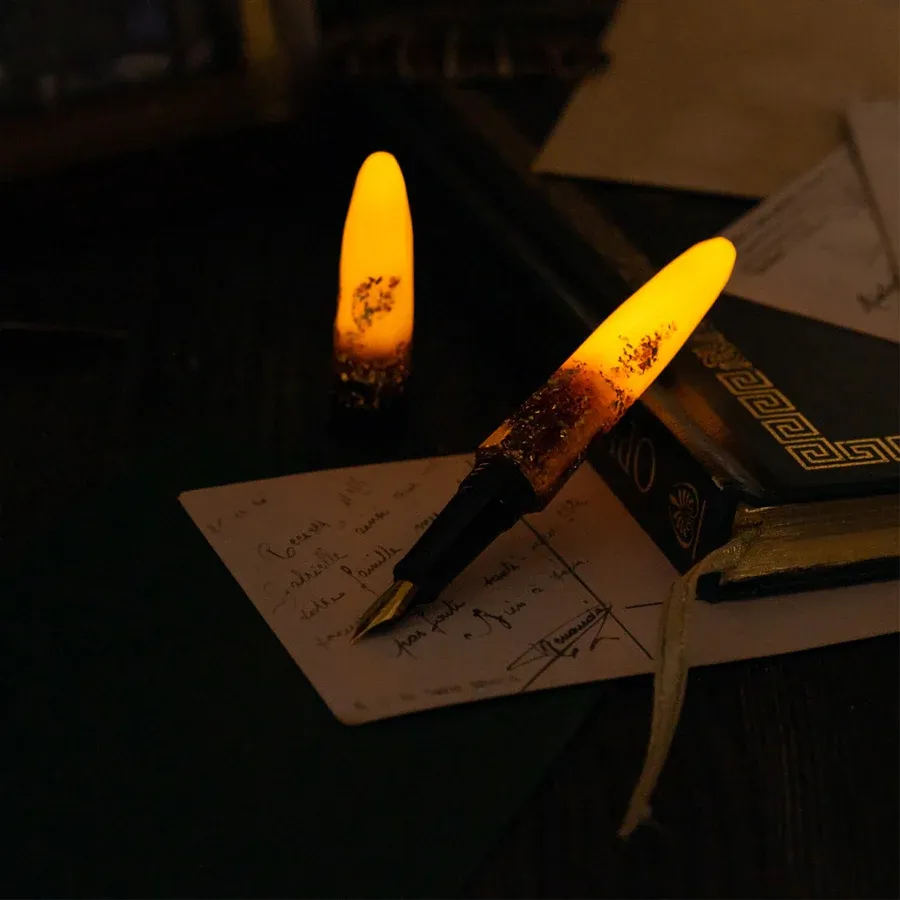 a fountain pen that's glowing yellow at both ends, propped on a book